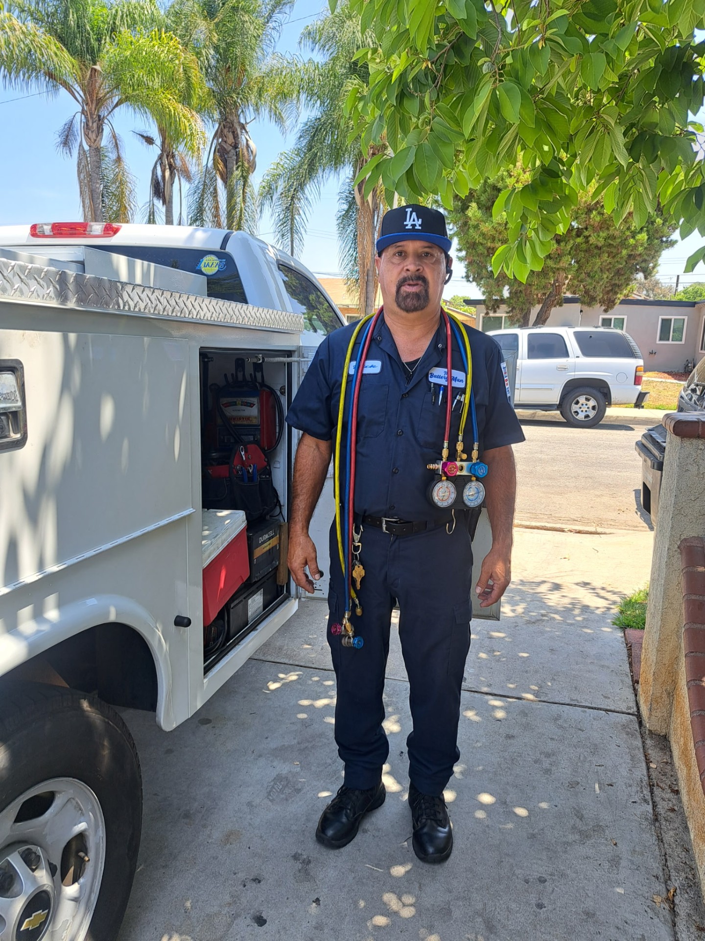 Rick with A/C manifold gauge hoses around his shoulders next to the service truck