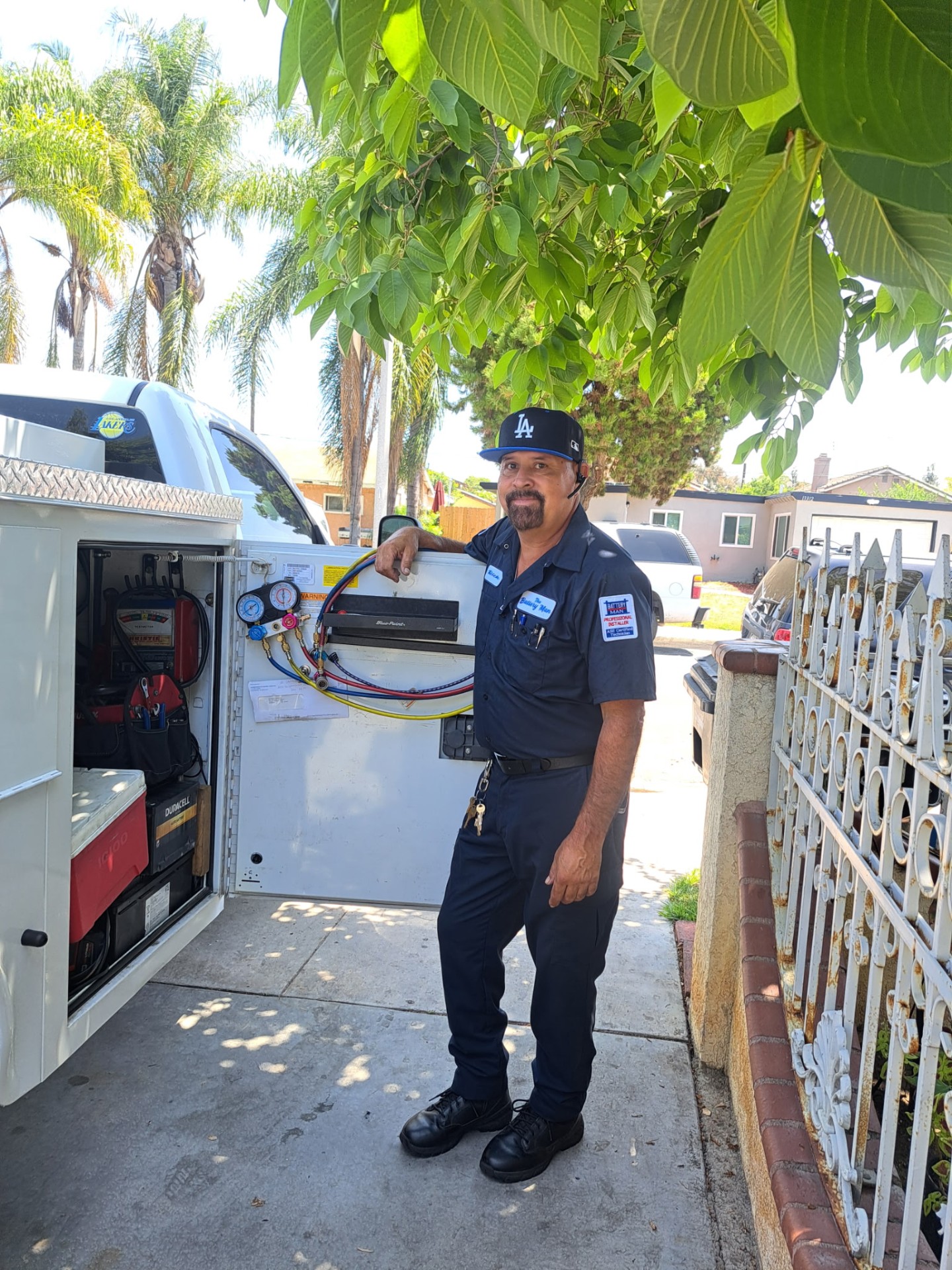 The Battery Man beside his mobile service truck holding a replacement car battery in Bellflower, California.